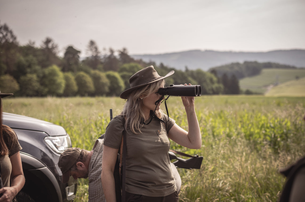 Eine Frau die im Feld steht mit einem Fernglas in der Hand