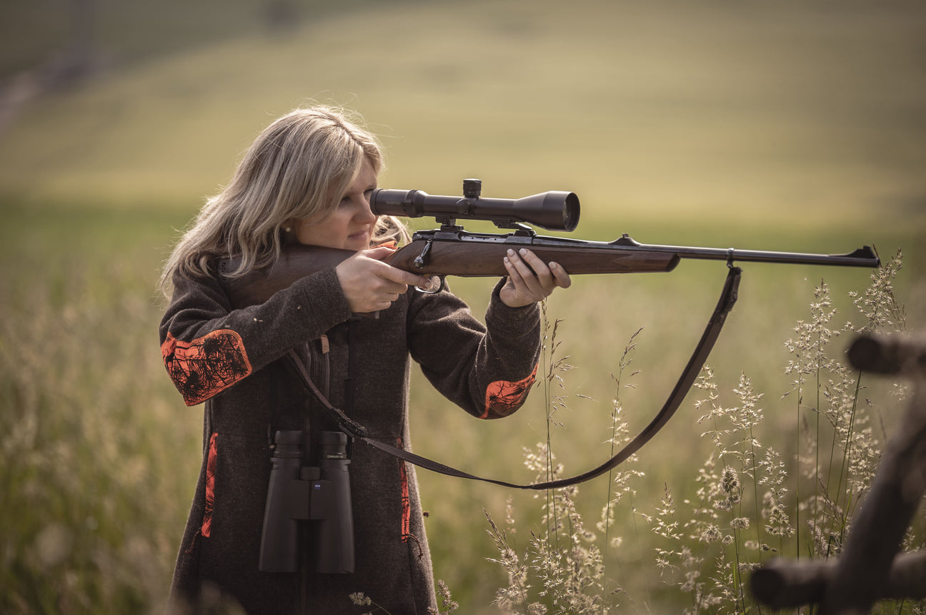 Eine Frau hält ein Gewehr und am Gewehr hängt ein Gewehrriemen